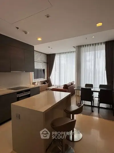 Modern open-layout kitchen and living area with stylish furniture and large windows.