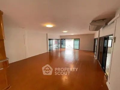 Spacious open-plan living area with large windows and terracotta flooring.