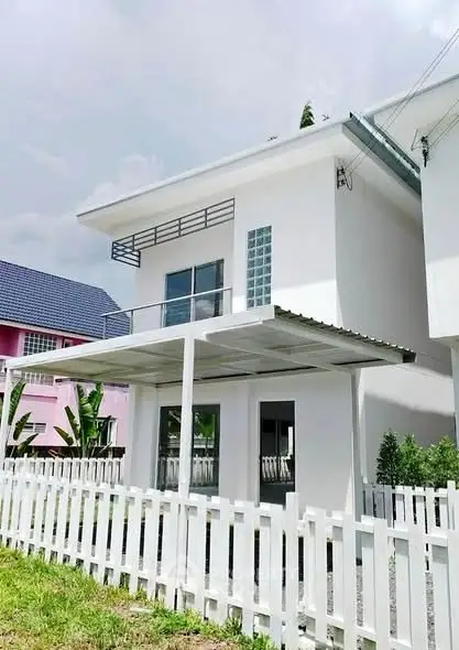 Modern white two-story house with balcony and fenced yard