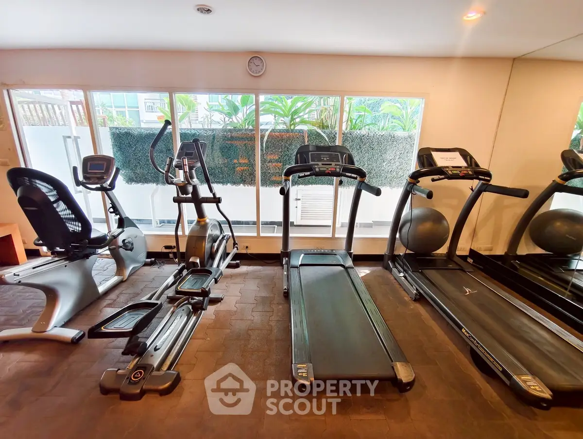 Modern gym with exercise equipment and large windows for natural light