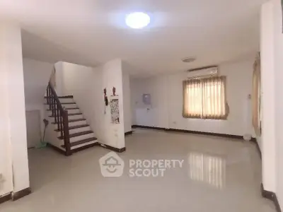 Spacious unfurnished living room with staircase and large window