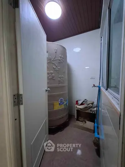 Compact utility room with water tank and storage space