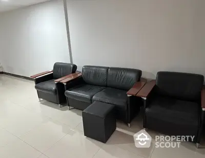 Modern office waiting area with sleek black leather seating and minimalist design.