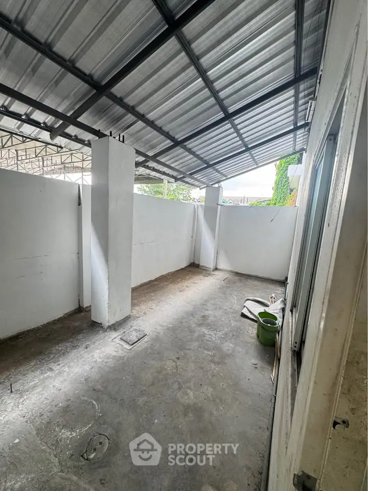 Spacious covered outdoor area with concrete flooring and metal roof, ideal for versatile use.