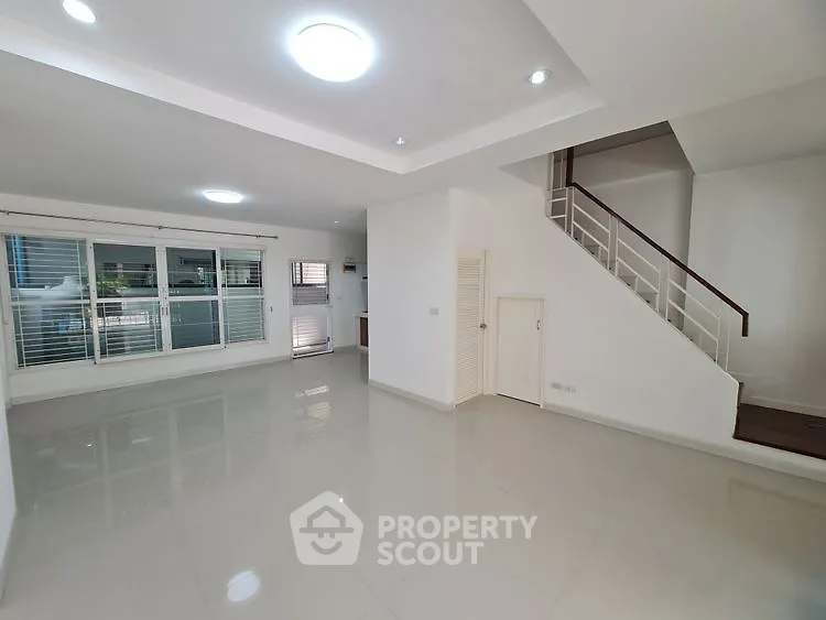 Spacious modern living room with sleek staircase and large windows