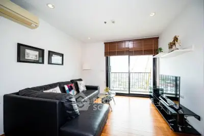 Modern living room with black leather sofa and balcony view