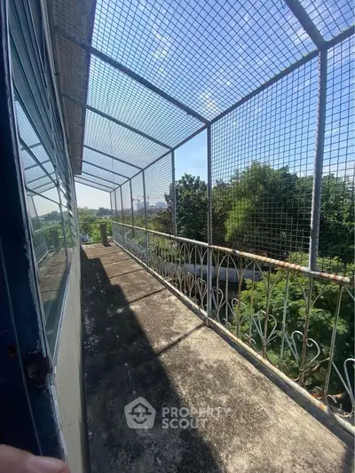 Spacious balcony with protective netting and lush green views, perfect for relaxation and outdoor enjoyment.