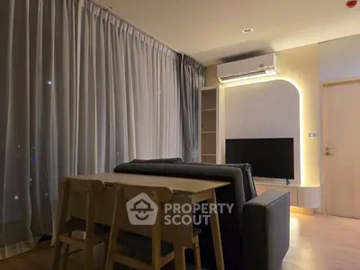 Modern living room with stylish furniture and ambient lighting, featuring a cozy dining area and sleek entertainment setup.