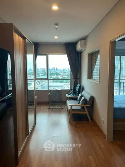 Modern apartment interior with city view, featuring cozy seating and wooden flooring.