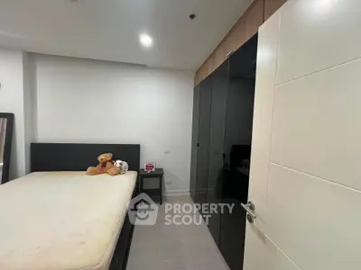 Modern bedroom with sleek black wardrobe and cozy bed featuring plush toys.