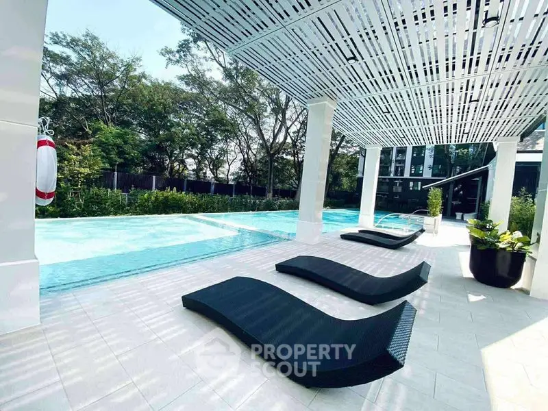 Luxurious poolside area with modern lounge chairs and lush greenery