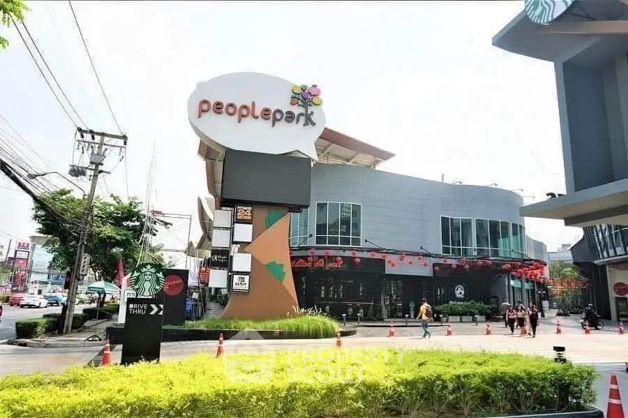 Modern shopping center exterior with vibrant signage and lush landscaping.