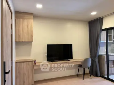 Modern living room with sleek wooden furniture and flat-screen TV, adjacent to a stylish kitchen.