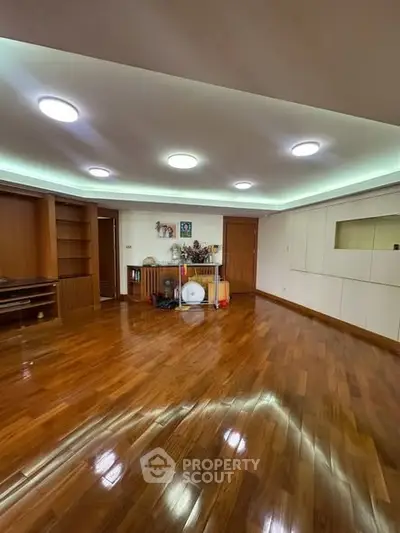 Spacious living room with polished wooden floors and modern lighting