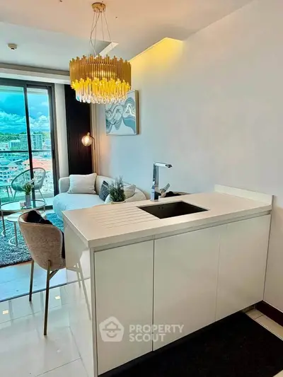 Modern open-plan living room with chic decor and city view, featuring elegant lighting and sleek kitchen island.