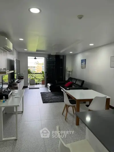 Spacious modern living room with sleek furniture and large windows offering a city view.