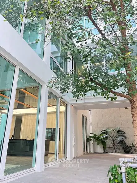 Modern building entrance with glass facade and lush greenery