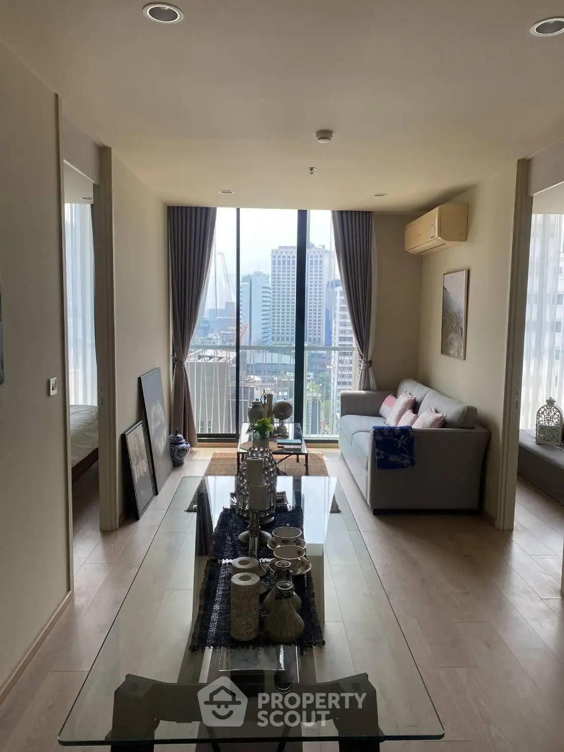 Modern living room with city view, stylish decor, and natural light in a high-rise apartment.