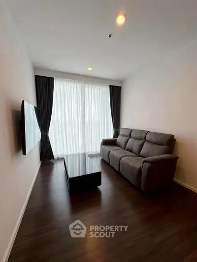 Modern living room with sleek dark flooring, plush sofa, and wall-mounted TV, perfect for relaxation.