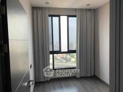 Bright room with large window offering city view, perfect for a cozy bedroom or study space.