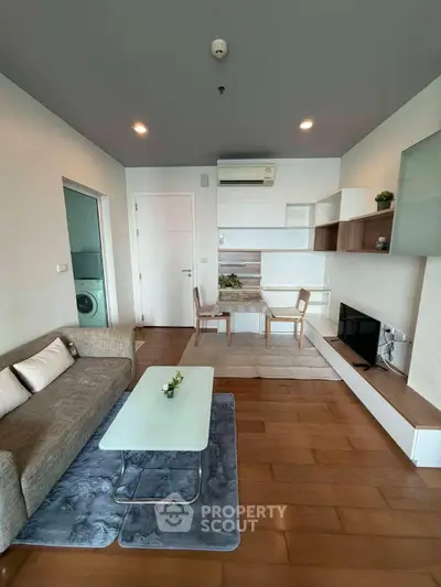 Modern living room with stylish furniture and wooden flooring, featuring a cozy sofa and a sleek coffee table.