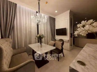 Elegant living room with chandelier, marble table, and plush seating in luxurious apartment.