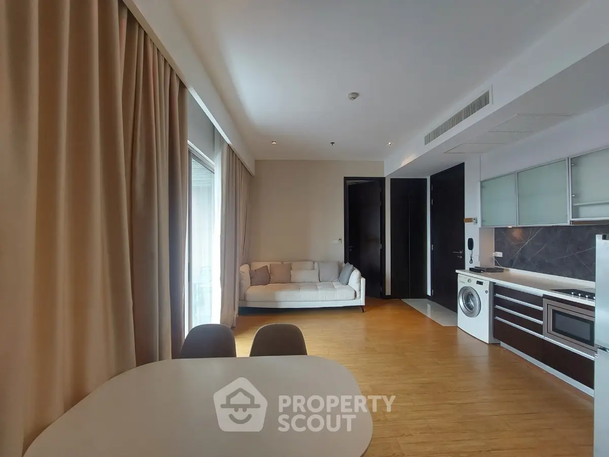 Modern open-plan living room with kitchen, featuring a cozy sofa and washing machine.