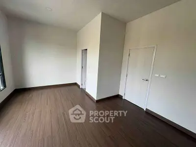 Spacious empty room with wooden flooring and white walls, ideal for customization.