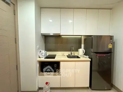 Modern compact kitchen with sleek cabinets and stainless steel appliances in a cozy apartment.