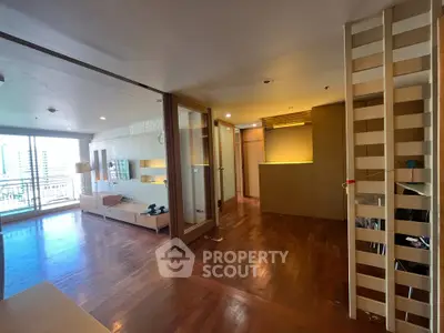 Spacious modern living room with wooden flooring and balcony view in a high-rise apartment.
