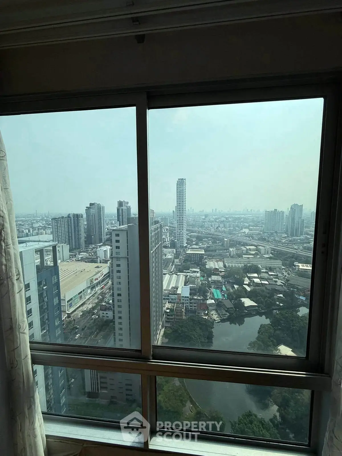 Stunning cityscape view from high-rise apartment window, showcasing urban skyline and serene landscape.
