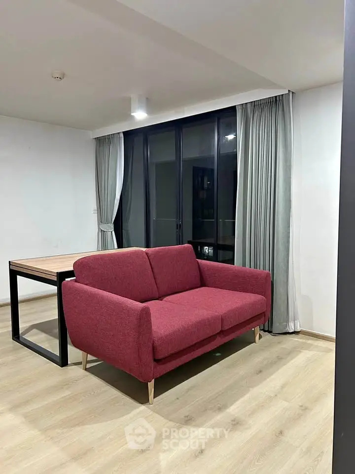 Modern living room with red sofa and large windows in a stylish apartment.
