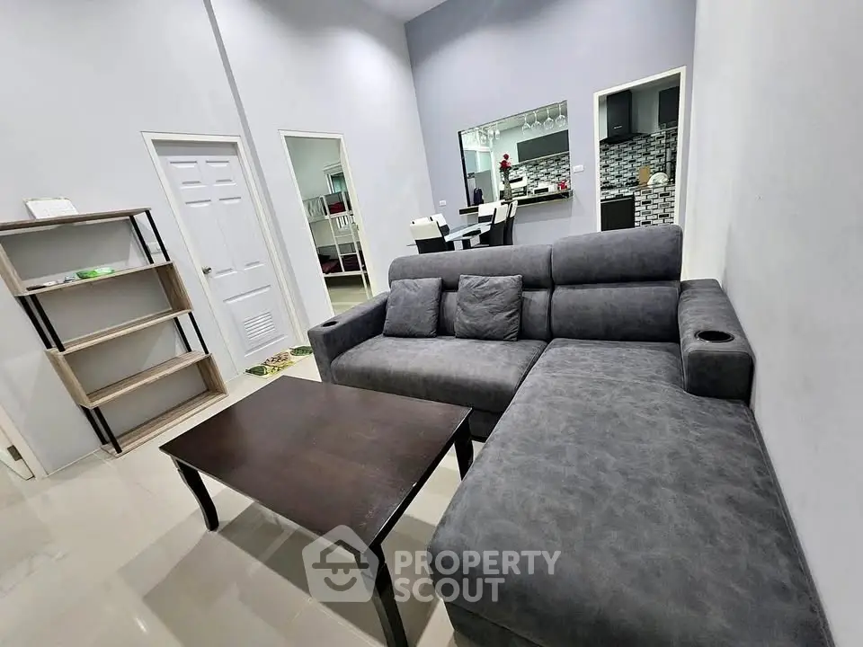 Spacious living room with modern gray sectional sofa and sleek dining area in open layout.
