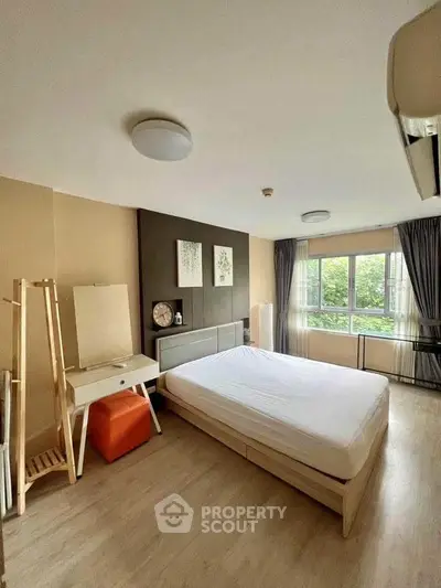 Spacious bedroom with modern decor and large window offering natural light and garden view.