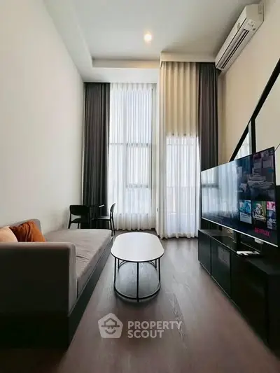 Modern living room with high ceilings, sleek furniture, and large windows for natural light.