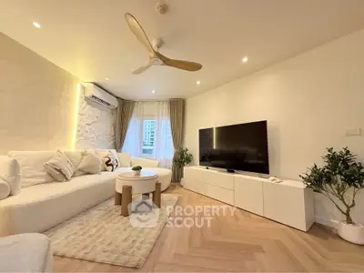 Modern living room with stylish decor, large TV, and cozy seating area.