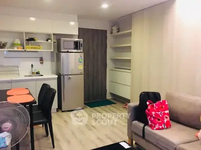 Modern open-plan living room with kitchen, featuring sleek appliances and cozy seating area.