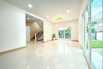 Spacious modern living room with large windows and garden view, perfect for family gatherings.