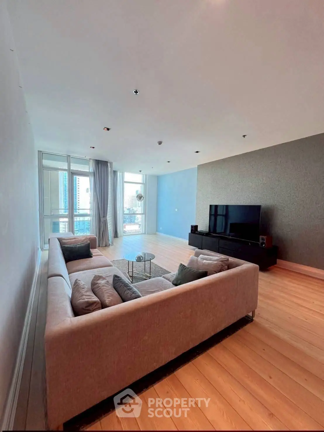 Spacious modern living room with large sofa and city view.