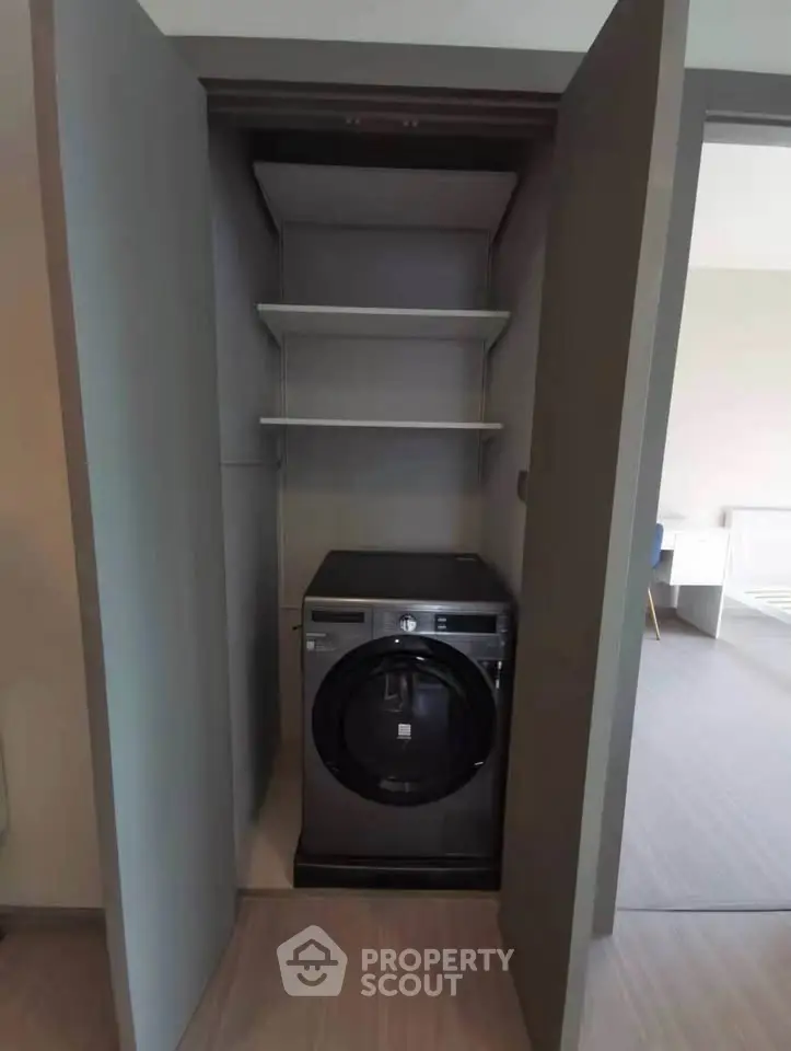 Modern laundry closet with sleek washing machine and storage shelves in stylish apartment.