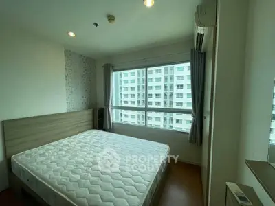 Spacious bedroom with large windows offering a city view in a modern apartment.