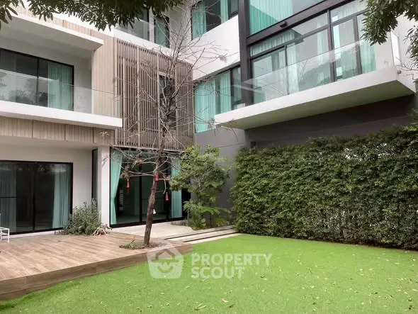 Modern apartment building with spacious balconies and lush green garden.