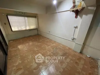 Spacious unfurnished room with tiled flooring and large window, ideal for customization.