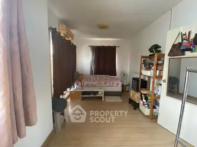 Cozy bedroom with wooden flooring, natural light, and organized storage space.