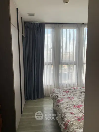 Cozy bedroom with large window and floral bedding in modern apartment