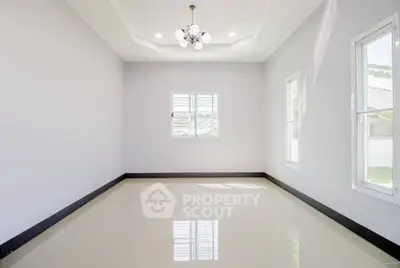 Spacious empty room with glossy tiled floor and modern chandelier