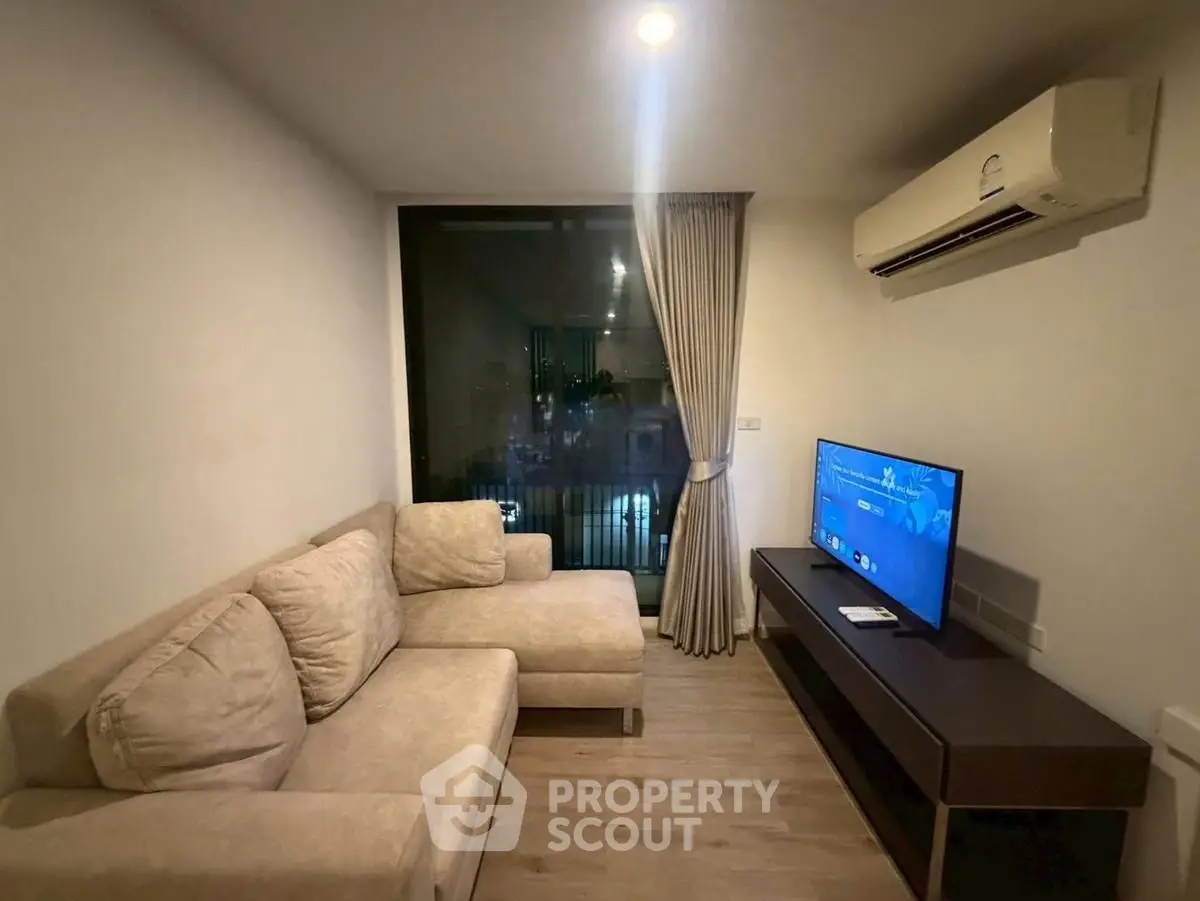 Cozy living room with modern sofa, air conditioning, and large window for natural light.