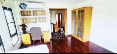 Spacious bedroom with wooden flooring and ample natural light, featuring a desk and glass cabinet.