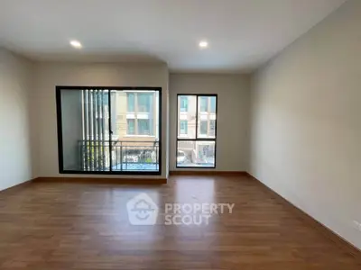 Spacious living room with large windows and wooden flooring in modern apartment.