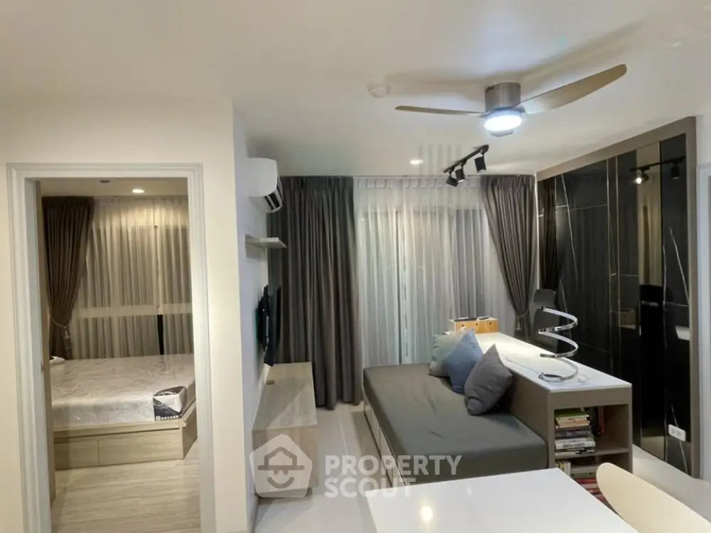 Modern studio apartment with sleek design, featuring a cozy living area and a glimpse of the bedroom.
